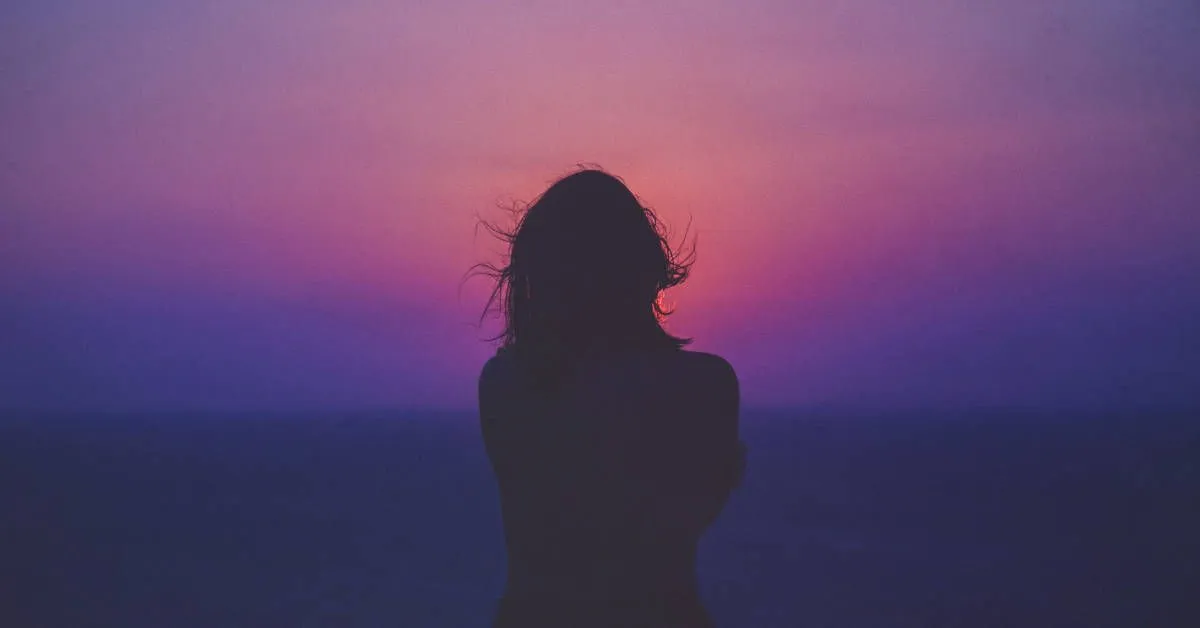 Fotografía de una mujer de espaldas observando el atardecer