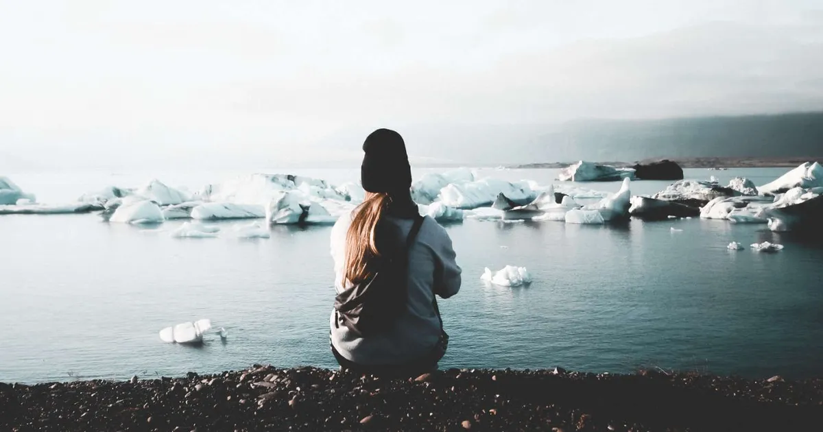 Chica de espaldas observa un mar con pedazos de hielo flotando