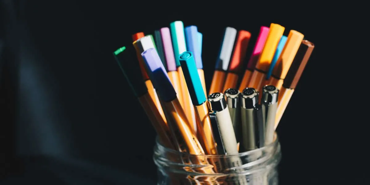 Fotografía de bote de cristal con rotuladores de colores