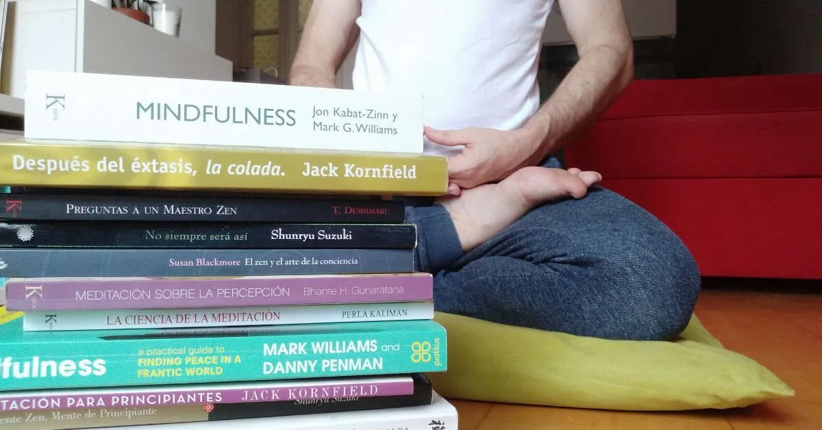 Meditando con una pila de libros sobre mindfulness y meditación delante