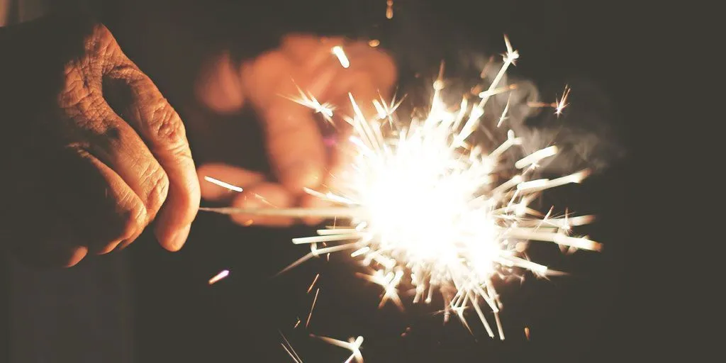 Fotografía de unas manos sujetando una bengala encendida.