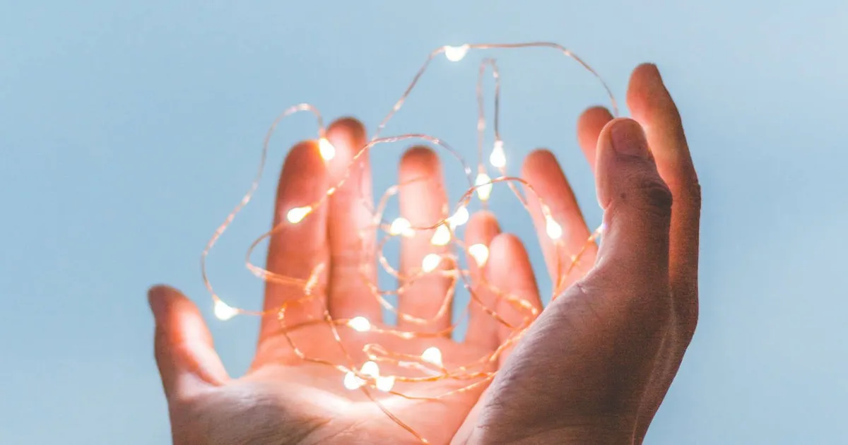 Manos en gesto de gratitud sosteniendo unas luces
